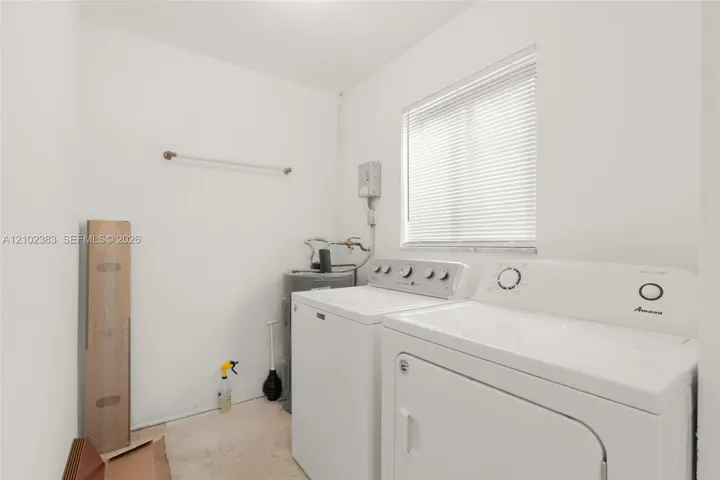 Laundry space featuring white walls, a horizontal window with adjustable blinds, and a built-in wall-mounted hanging rod