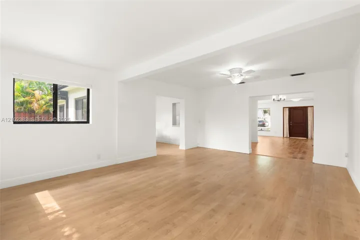 Open-concept interior featuring wood-finish flooring, a ceiling fan, and multi-paned windows with black frames