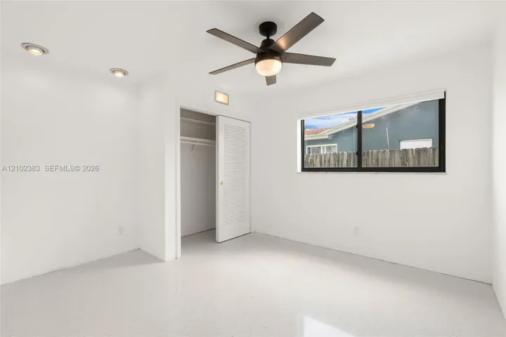 Bedroom 1 Neutral-toned terrazzo flooring, recessed lighting, ceiling fan with integrated light, and louvered closet door