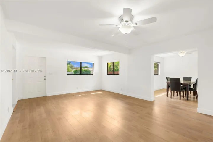 Family roomfeaturing wood-finish flooring, white walls, and a ceiling fan with integrated lighting