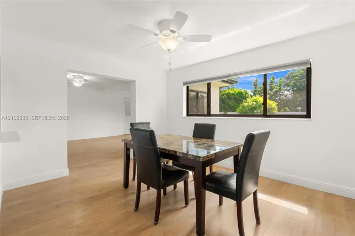 Breakfast area featuring wood-finish flooring, a neutral color palette, a wide-panel window, and a ceiling-mounted light fixture with a fan