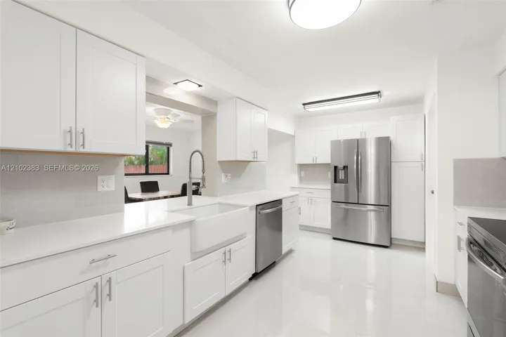 Kitchen featuring white cabinetry, quartz countertops, a farmhouse-style apron sink, stainless steel appliances, and tile flooring