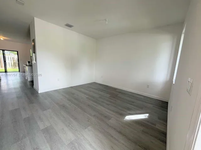 Neutral-toned wood-finish flooring, white walls, and large window