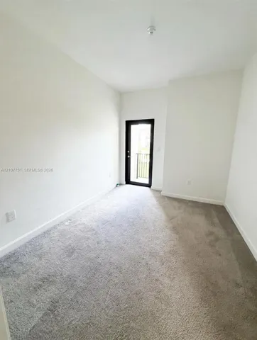 Neutral-toned wall-to-wall carpeting and glass-paneled door with black frame providing exterior access