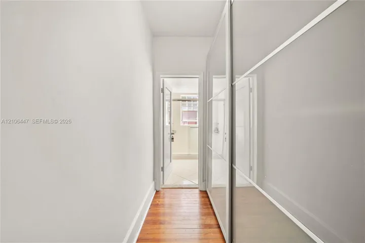Full-length sliding wardrobe panels featuring a glossy finish and metallic trim, set against wood-finish flooring