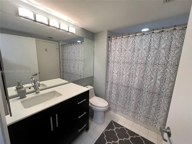 Dark wood-finish vanity with rectangular integrated sink, white composite countertop, polished chrome faucet, full-width vanity mirror, and linear light fixture