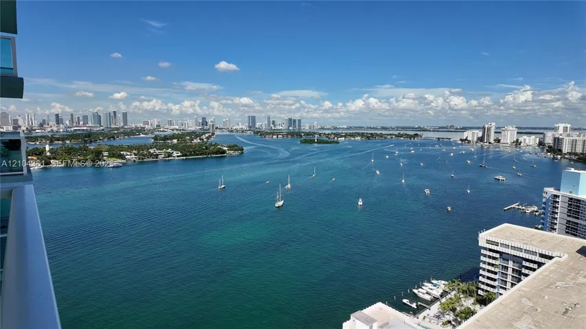 Panoramic water and city skyline outlook featuring a wide expanse of bay, anchored boats, and distant high-rise architecture
