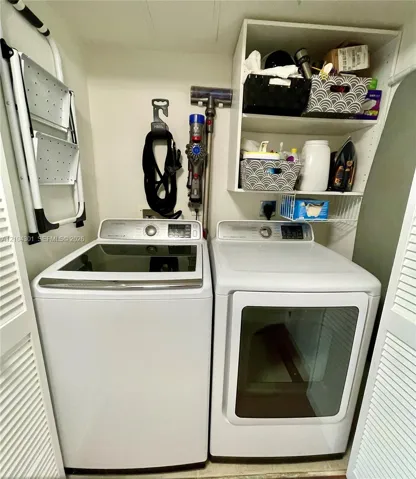 Laundry area featuring top-loading washer and front-loading dryer, built-in upper shelving, and louvered folding doors