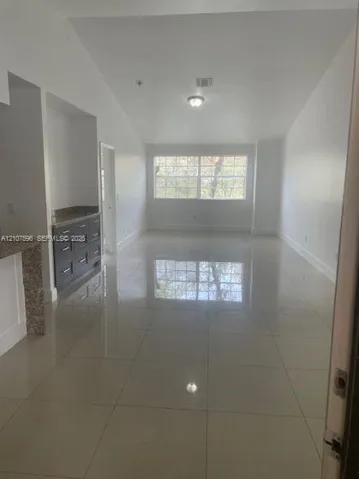 Vaulted ceilings, large-format tile flooring, built-in cabinetry, stone-surface counters, and oversized windows