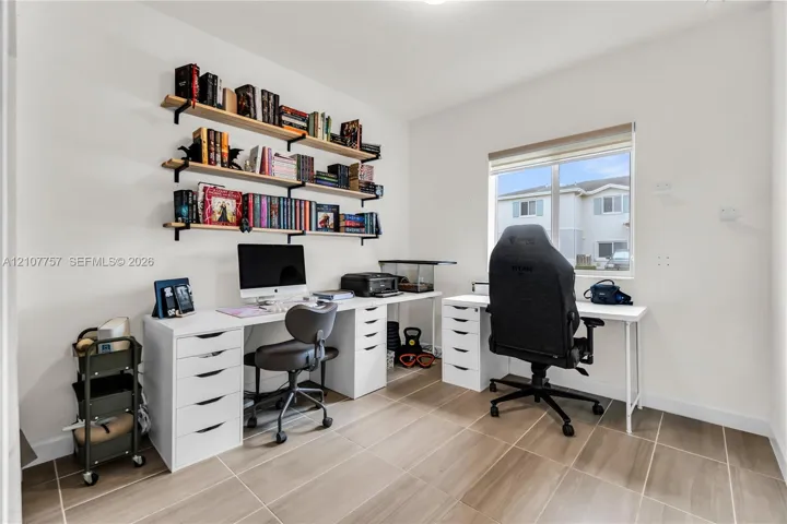 Neutral-toned room featuring light-colored tile flooring, white walls, and a window with a fitted roller shade