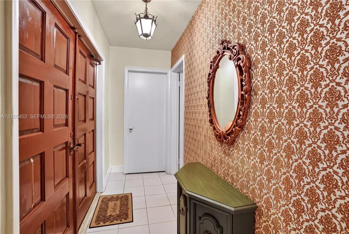 Entryway featuring double wood-paneled doors, ceramic tile flooring, and patterned wallcovering