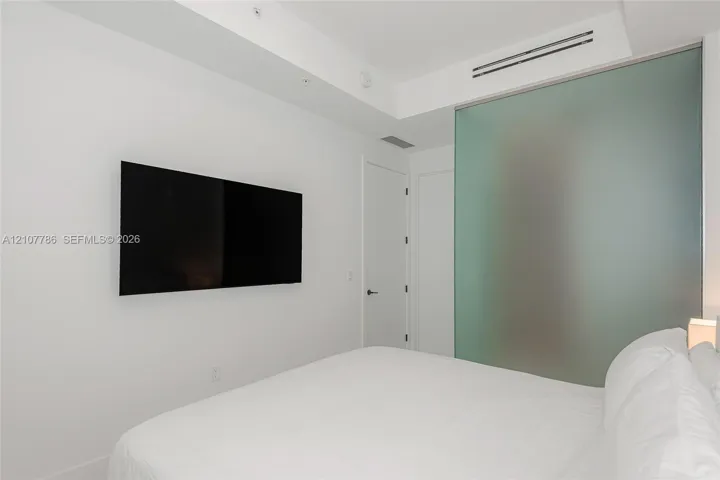Interior space featuring minimalist design, a recessed ceiling system with integrated climate control, and a large frosted glass partition