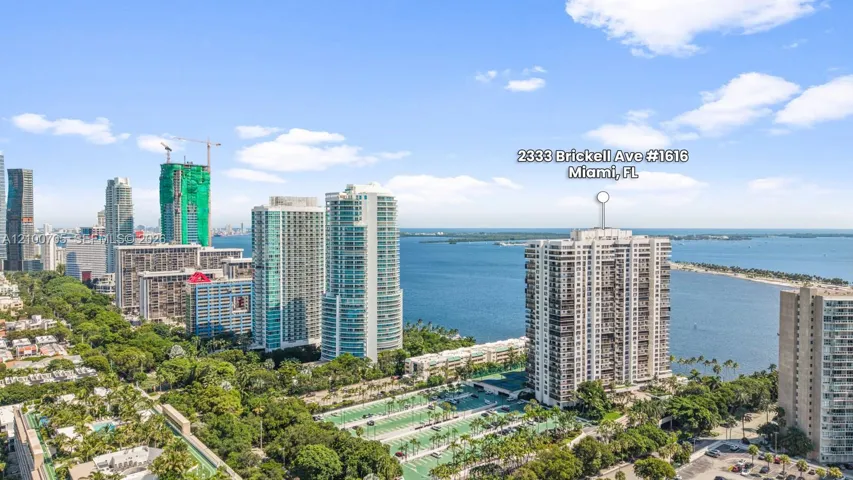 High-rise residential building featuring expansive coastal water frontage, direct bay exposure, and an integrated paved parking facility