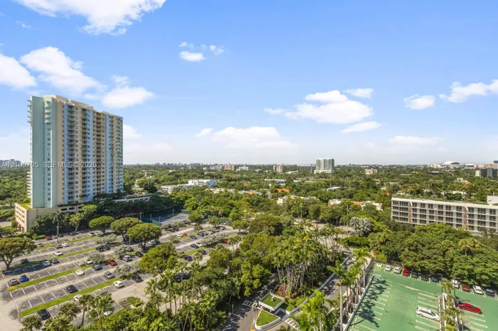 Elevated perspective featuring sprawling canopy coverage, mature palm trees, paved parking infrastructure, and mid-rise residential architecture