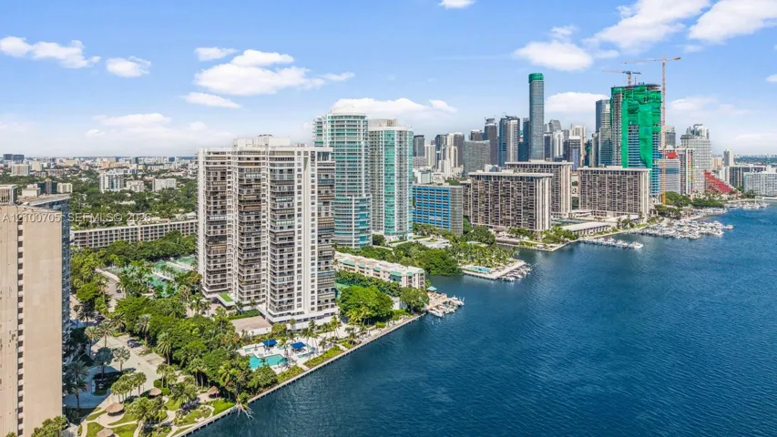 Aerial perspective featuring waterfront high-rise buildings, deep-water boat slips, on-site swimming pools, and landscaped grounds with mature palm trees