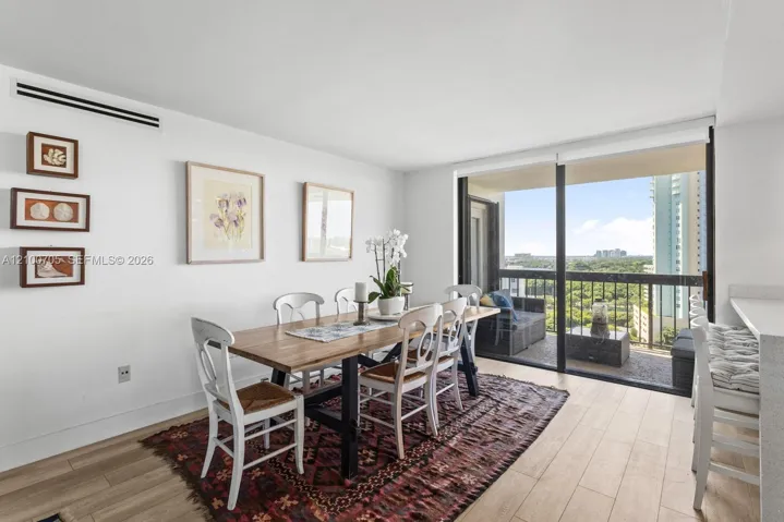 Dining area featuring wood-finish flooring, floor-to-ceiling sliding glass doors, and access to an exterior balcony