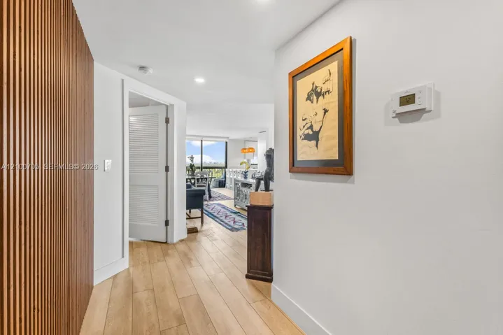 Interior hallway featuring a floor-to-ceiling vertical wood slat accent wall, recessed lighting, and wood-finish flooring
