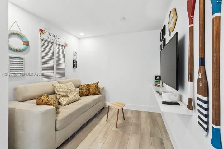 Interior space featuring wood-finish flooring, recessed lighting, white louvered window shutters, and a wall-mounted floating shelf