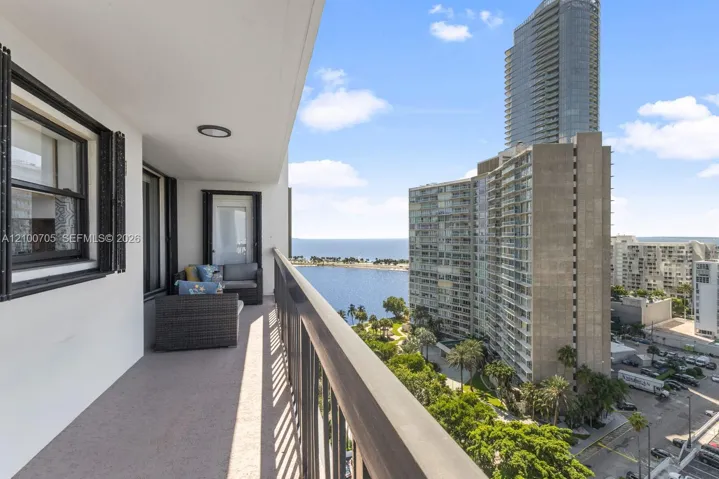 Covered balcony featuring concrete flooring, a metal railing, and direct water access