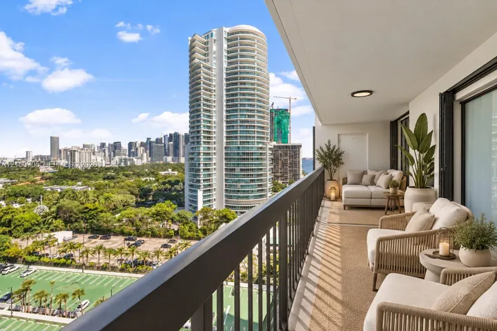 Covered balcony featuring black metal railings, recessed lighting, and expansive city skyline backdrop