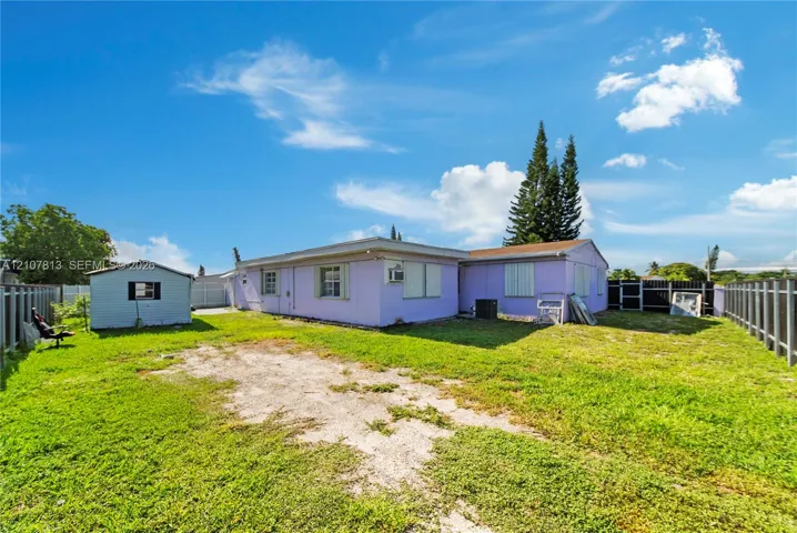Expansive backyard featuring a grass lawn, perimeter fencing, and an auxiliary storage structure