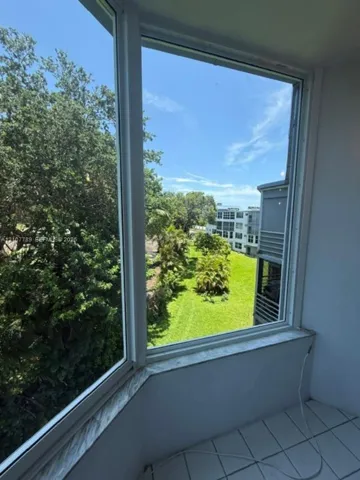 Floor-to-ceiling multi-panel windows featuring a stone-topped sill, white tile flooring, and exterior greenery