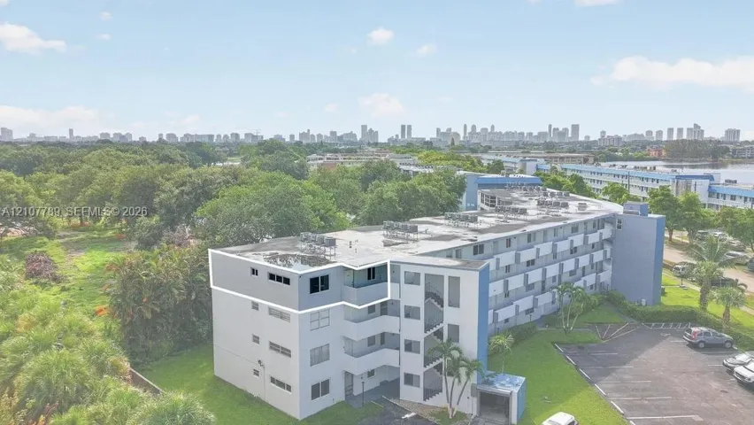 Multi-story residential building featuring a flat roofline, neutral exterior facade with blue accents, and an expansive skyline backdrop