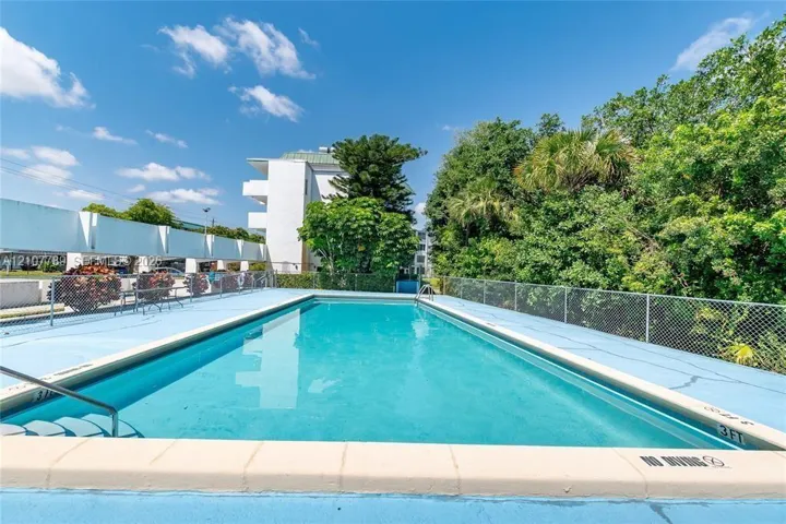 Outdoor swimming pool featuring a concrete deck and a chain-link security fence