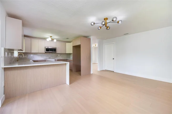 Kitchen featuring flat-panel cabinetry, quartz countertops, wood-finish flooring, gold-tone hardware, and a multi-bulb geometric light fixture