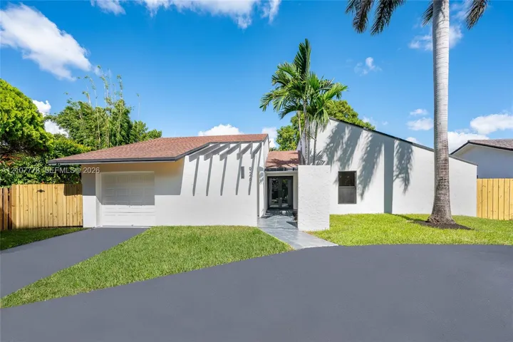 Contemporary exterior featuring white stucco finish, architectural pergola, attached garage, and paved entryway