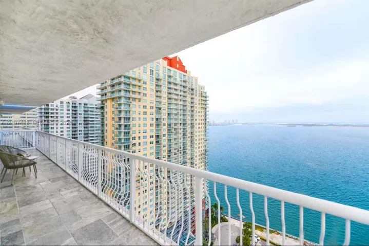 Covered balcony featuring stone-tile flooring and a white metal railing