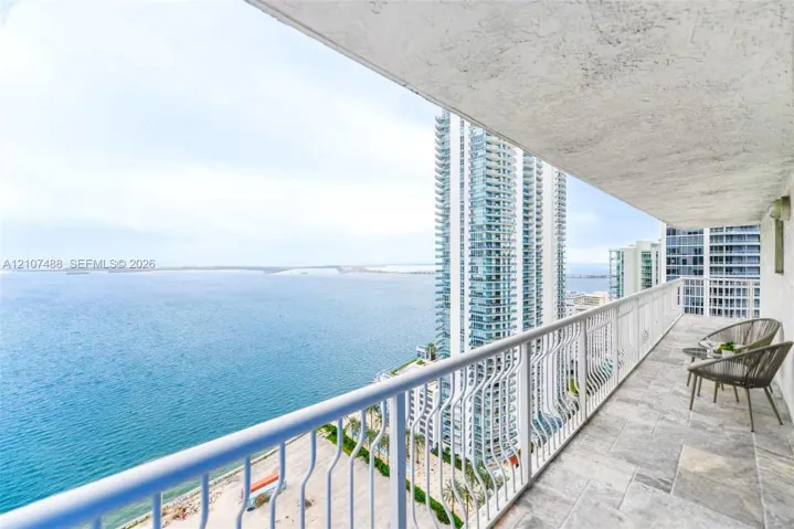 Covered balcony featuring stone-finish tile flooring and a white metal railing