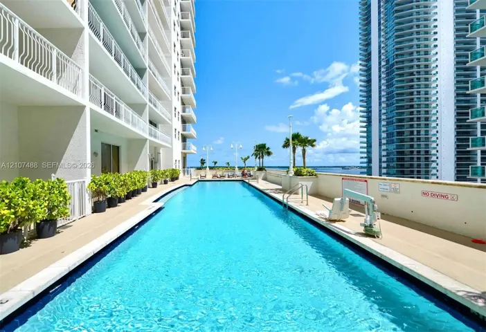 Outdoor swimming pool featuring a concrete deck, metal railings, perimeter planter boxes, and water-level lighting