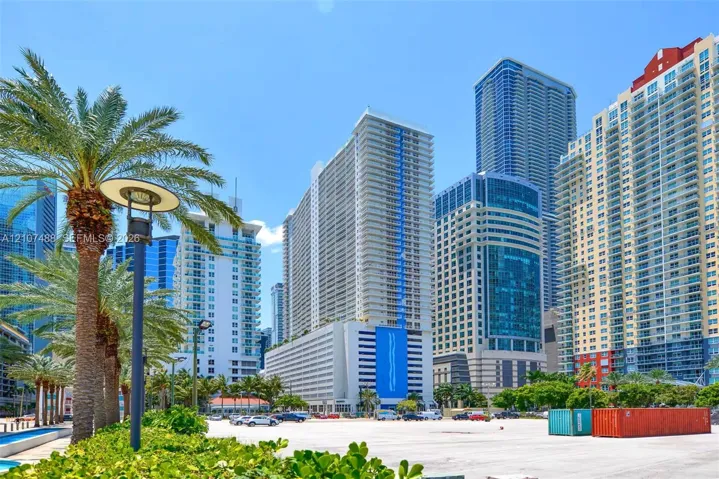 Urban high-rise architecture featuring glass facades, concrete exterior cladding, blue structural accents, and mature palm trees