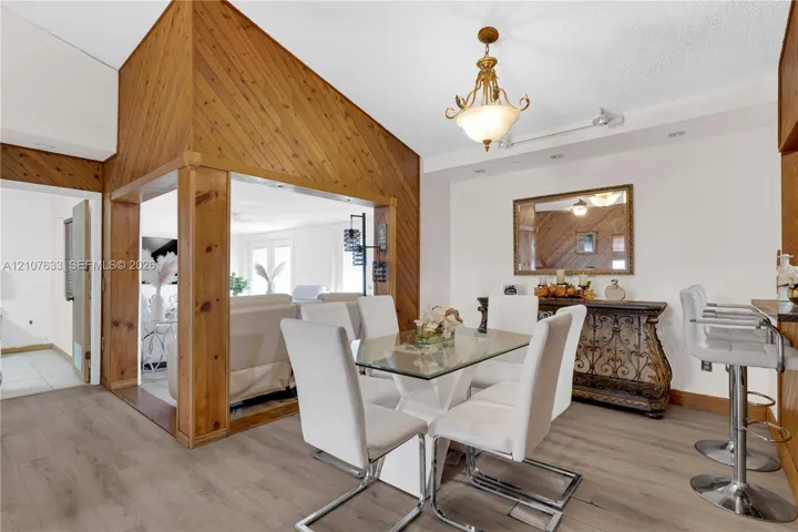 Dining area featuring diagonal wood-panel accent walls, wood-finish flooring, and a decorative multi-arm chandelier