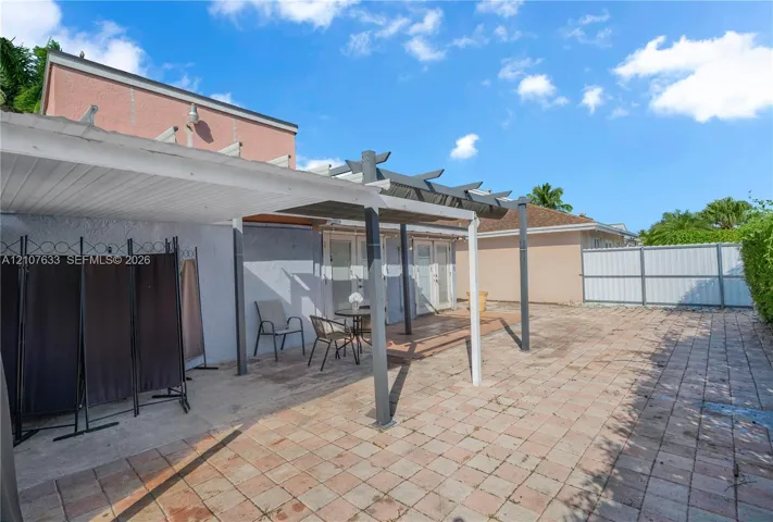 Rear exterior space featuring a paved patio, a covered pergola, and partial privacy fencing