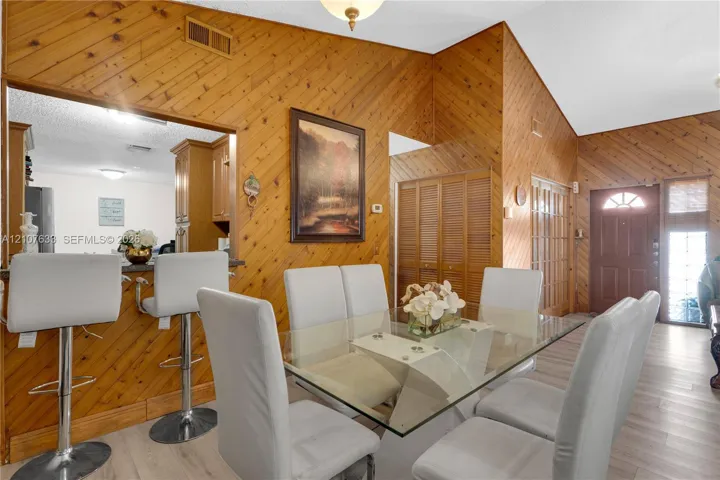 Vaulted ceilings, wood-paneled walls, and light-toned wood-finish flooring featuring a breakfast bar with built-in cabinetry and louvered closet doors