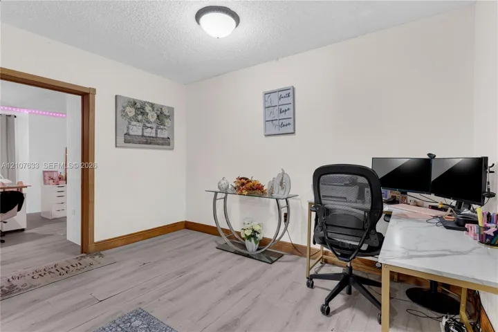 Wood-finish flooring, natural wood door casing, and a dome-style flush-mount ceiling fixture