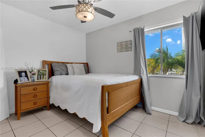 Room featuring large-format neutral floor tile, a central ceiling fan with an integrated light fixture, and a single-pane window