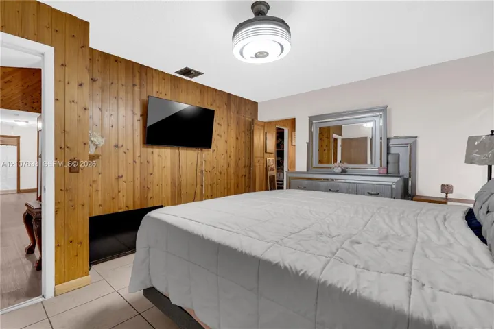Vertical wood-paneled accent wall, neutral ceramic tile flooring, and a modern circular flush-mount ceiling fixture