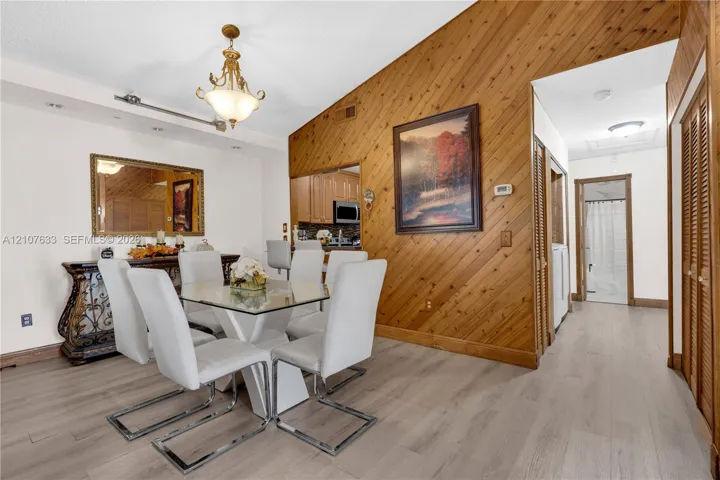 Vaulted ceiling featuring diagonal wood-plank paneling, wood-finish flooring, and ornate hanging light fixture