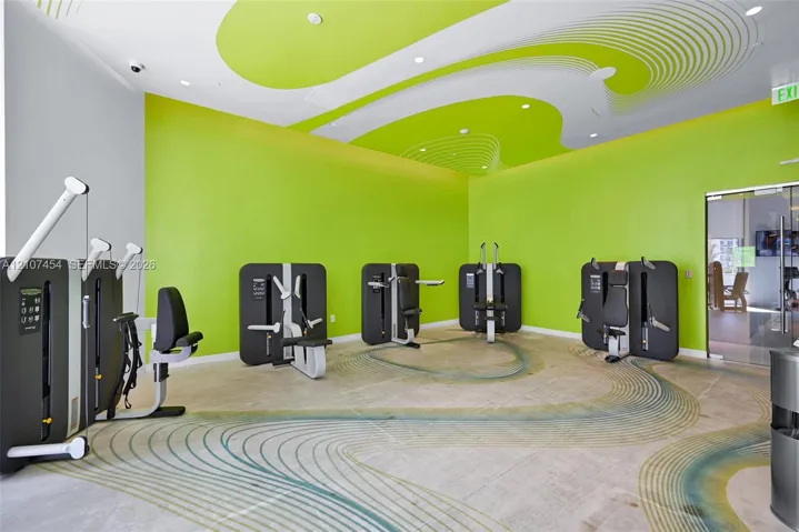 Fitness center featuring polished concrete flooring with a decorative inlay pattern, high ceilings with stylized graphic accents, and recessed lighting