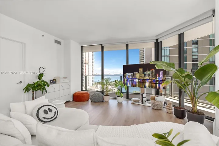 Floor-to-ceiling windows, wood-finish flooring, and an attached balcony with metal railing
