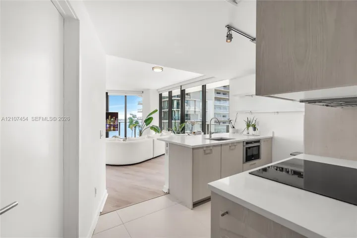 Kitchen featuring light wood-finish cabinetry, white countertops, built-in cooktop, and floor-to-ceiling windows