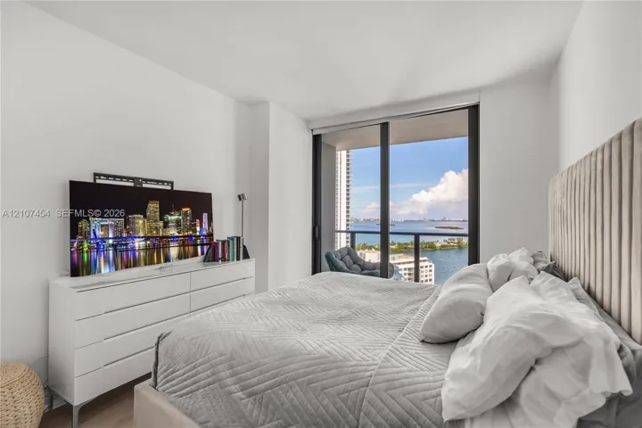 Floor-to-ceiling sliding glass door, private balcony with metal railing, and light-toned flooring