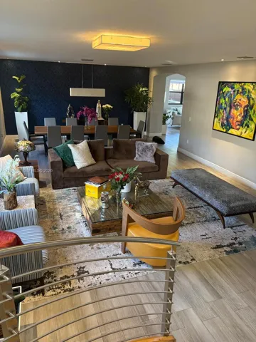 Open-concept space featuring wood-finish flooring, a textured dark navy accent wall, recessed lighting, and a stainless steel cable railing system