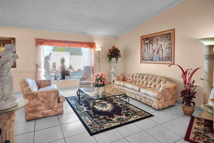 Living area featuring a vaulted ceiling with crown molding, large picture window, and ceramic tile flooring