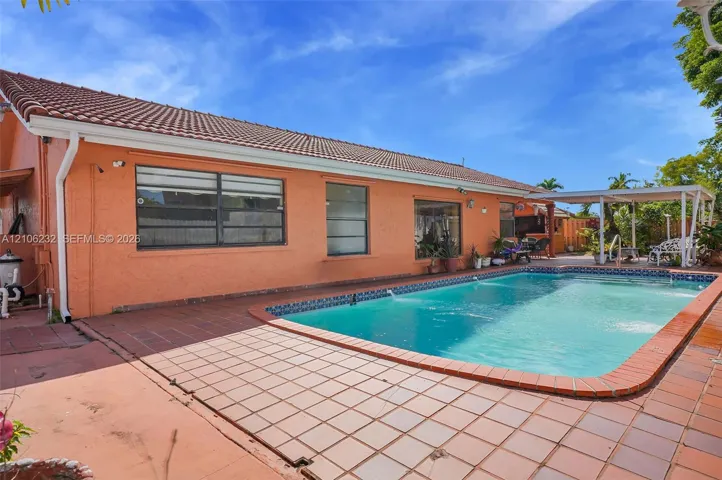 Stucco exterior featuring a tile roof, an in-ground pool with tile coping, and a covered patio​​‌​​​​‌​​‌‌​‌‌​​​‌‌​‌​‌​‌​​​‌​​ area