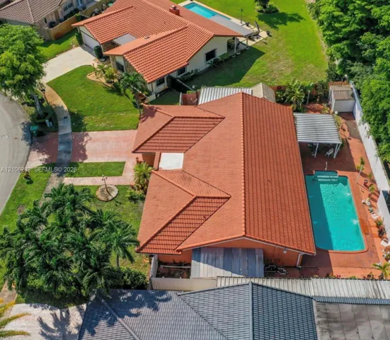 Tile roof residence featuring a paver driveway, an in-ground swimming pool, a covered patio, and landscaped grounds