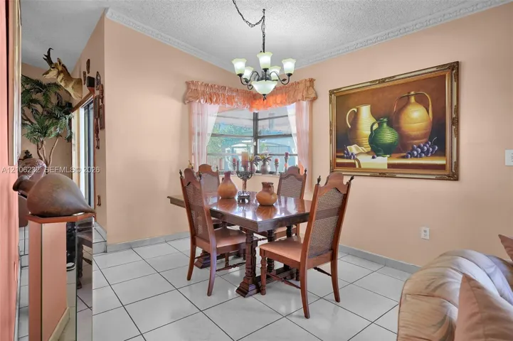 Dining area featuring large-format ceramic tile flooring, crown molding, a corner window configuration, and a multi-arm chandelier